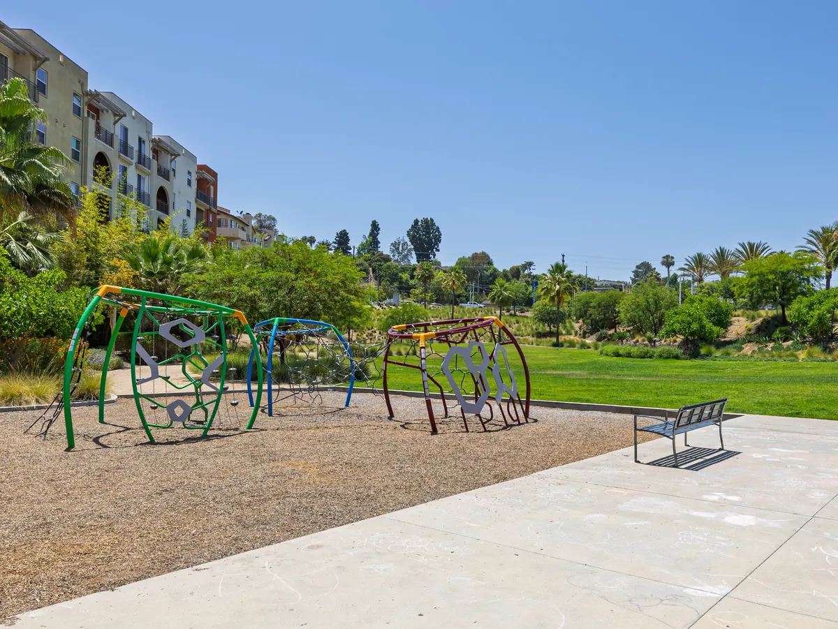A community playground with climbing structures and bench seating at Ponte Vista in San Pedro