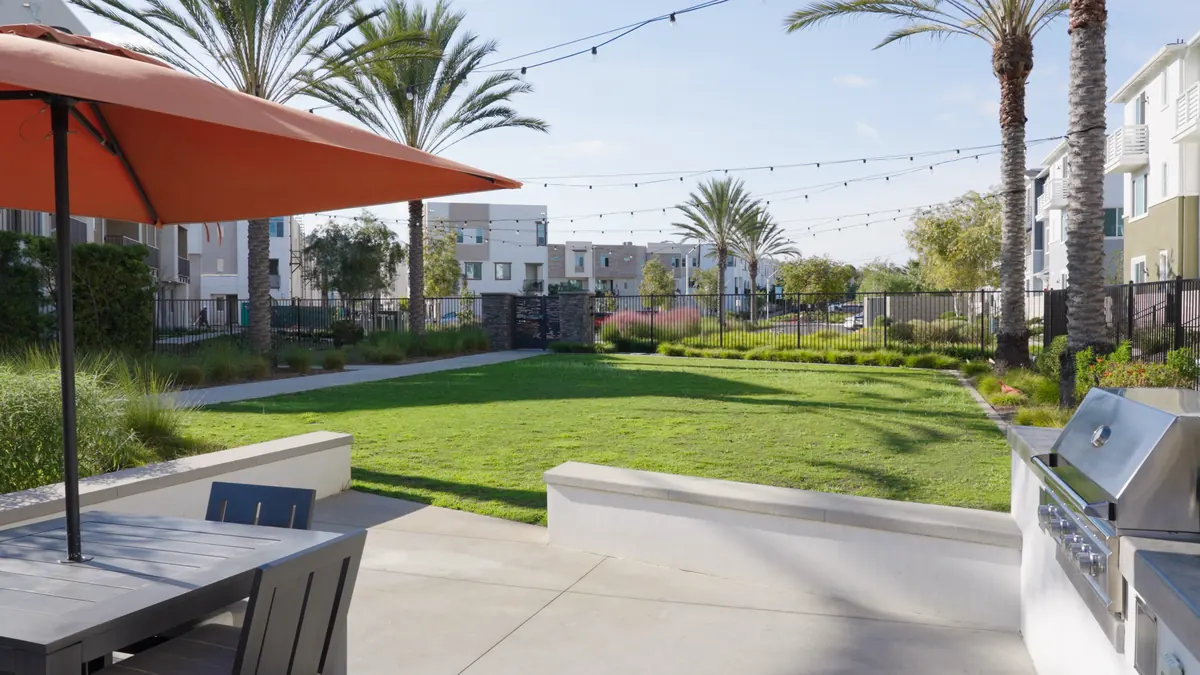 An open community lawn with string lights and umbrella seating at Ponte Vista in San Pedro