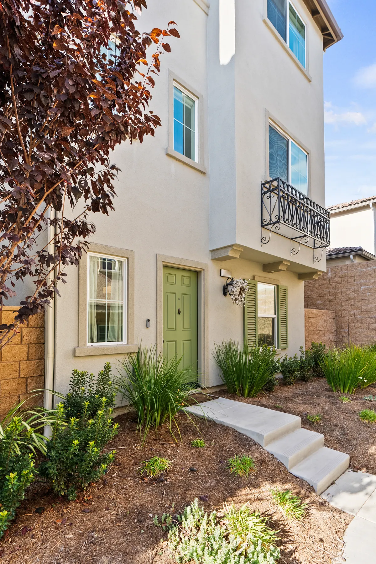 Front entrance of a three-story Skyview home with a sage-green door and balcony at Ponte Vista