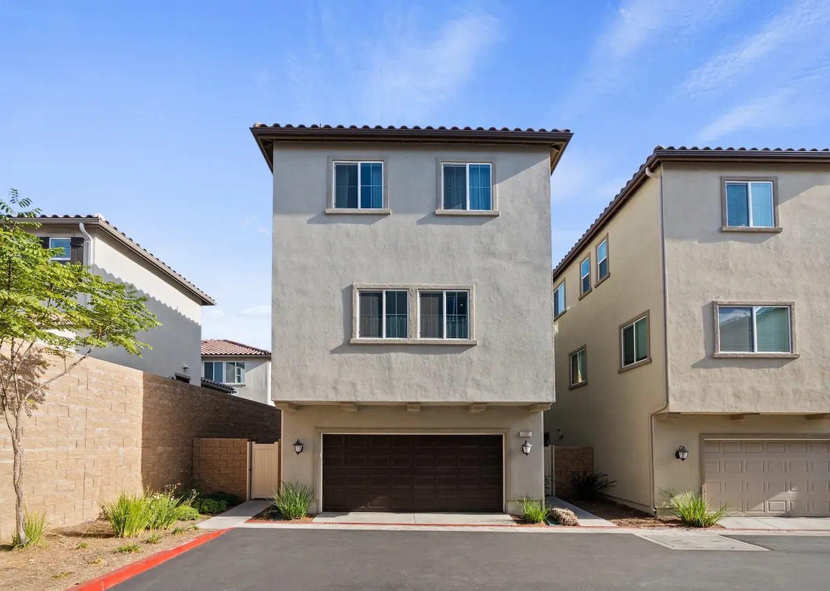 Garage side of a detached three-story Skyview home at Ponte Vista in San Pedro, with a two-car garage and tile roof